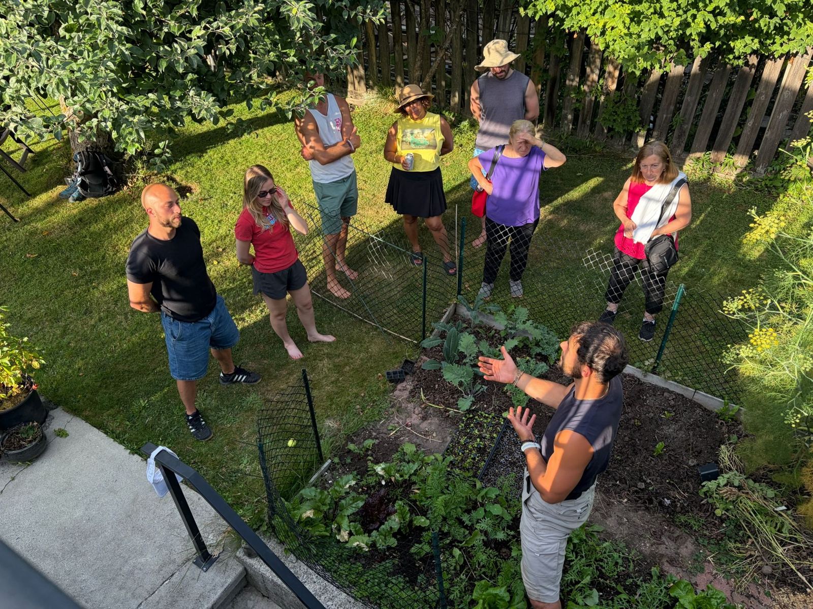 Overhead view of Nathan talking with a group gathered around a garden bed