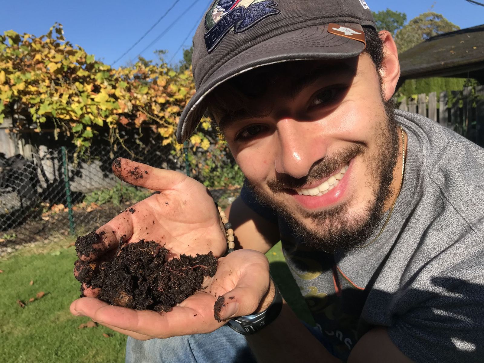 Nathan smiling and holding a handful of rich dark soil
