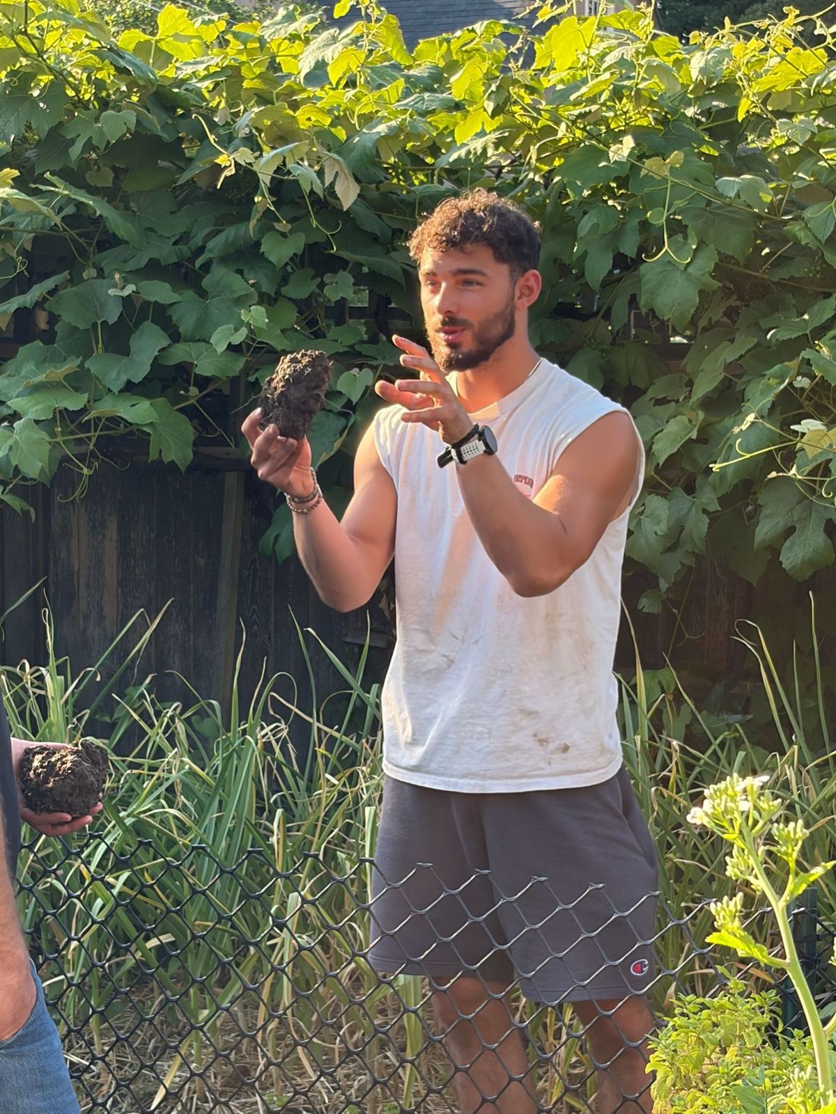 Nathan holding up a beet seedling while teaching in a backyard garden