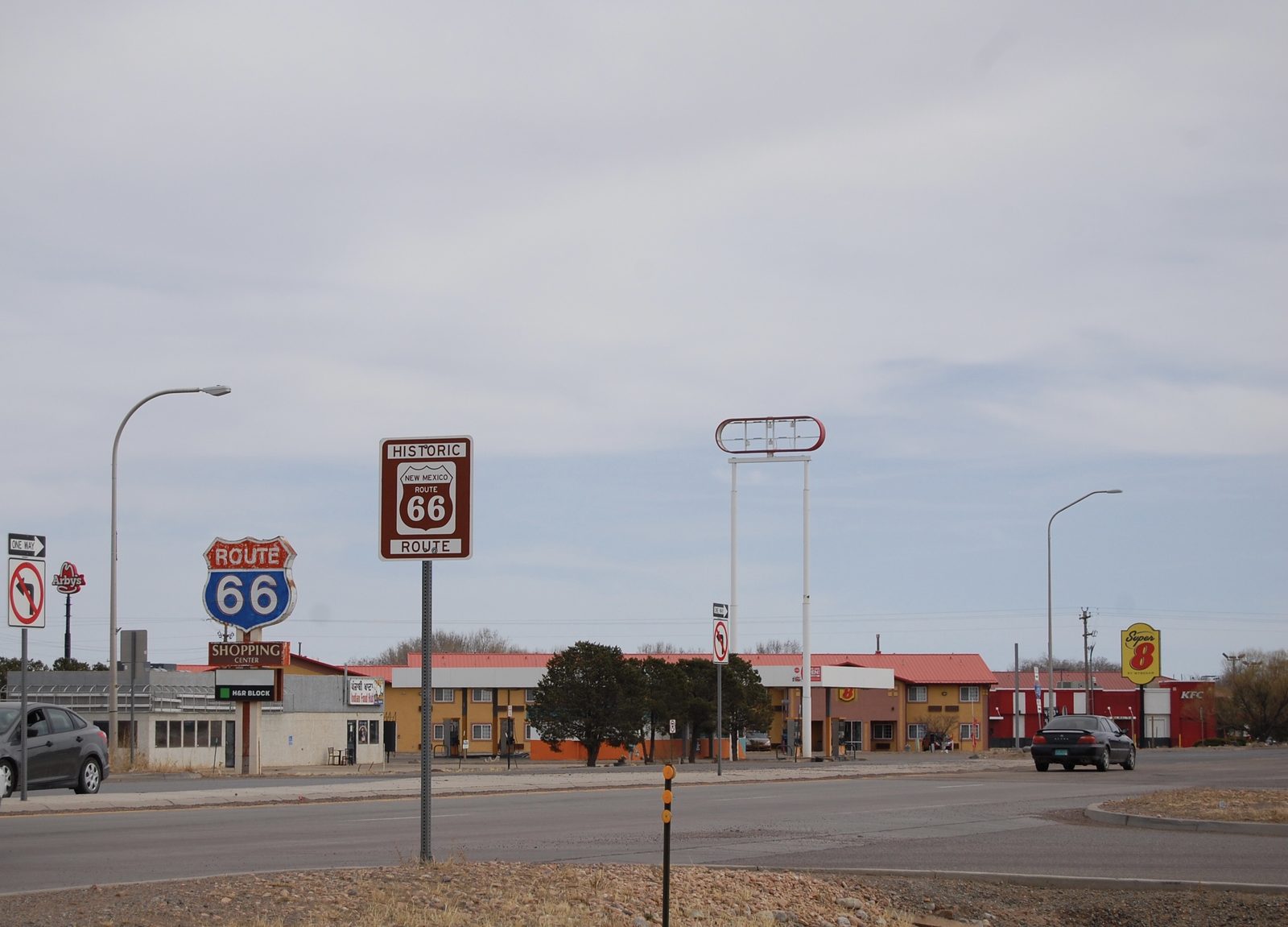 Historic Route 66 signs along a quiet New Mexico roadside under an overcast sky