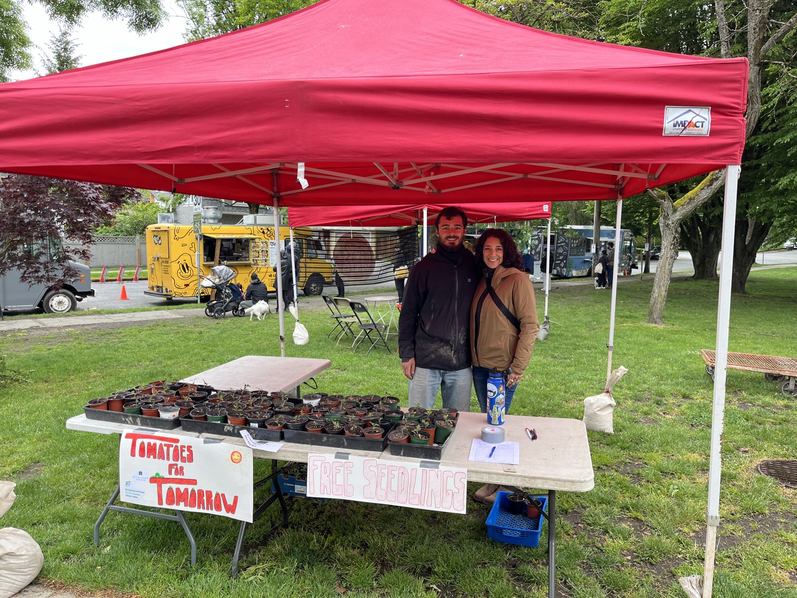Nathan and a volunteer at the Tomatoes for Tomorrow stand in a park
