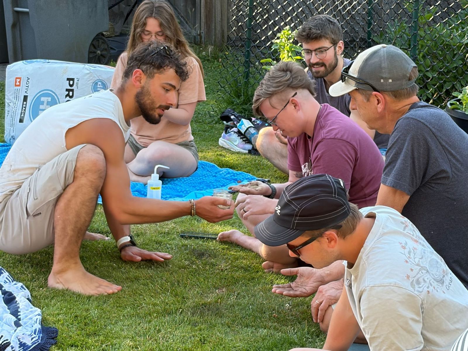 Nathan showing soil to a small group sitting on the lawn